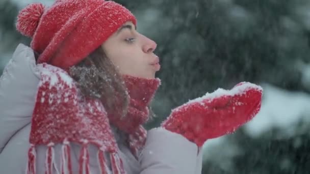 Feliz chica emocionada disfrutando de frescura helada y jugando con nieve fresca. 4k cámara lenta juguetona risueño mujer sopla nieve de mitones en el parque de invierno después de nevadas en el día de invierno helada — Vídeos de Stock