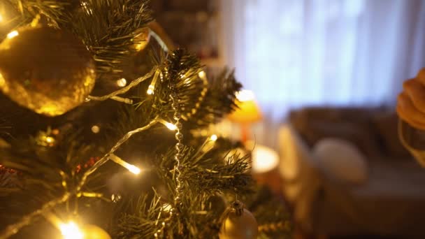Close up slow motion of beautiful smiling Woman decorates christmas tree at home with bulbs. making nice festive athmosfere in home interior and celebrating xmas and happy new year — Stock Video