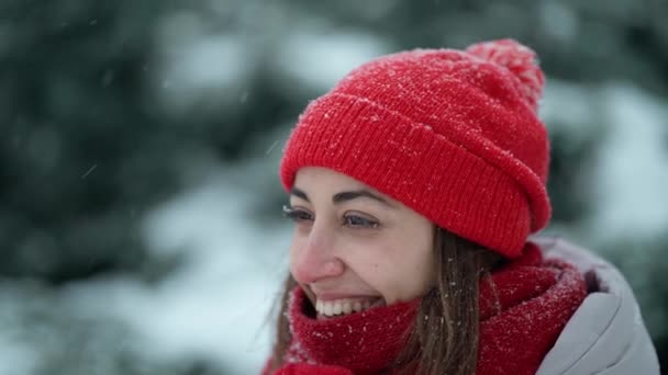 Super close up happy smiling woman in knitted hat and scarf in snowy winter park at frizzy day with snowflakes. woman exhales steam, snowflakes on her face. Happy winter time, having fun. — Stock Video