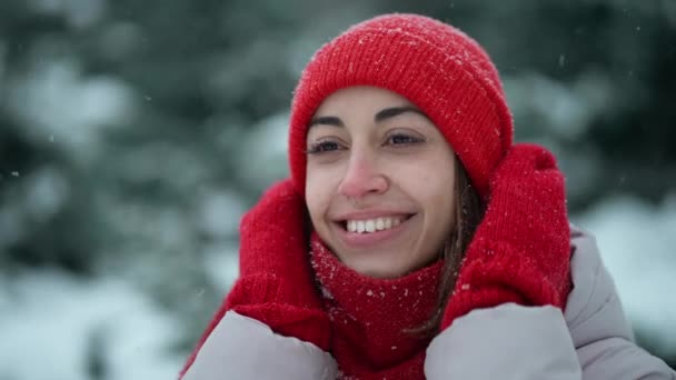 Super close up happy smiling woman in knitted hat and scarf in snowy winter park at frizzy day with snowflakes. woman exhales steam, snowflakes on her face. Happy winter time, having fun. — Stock Video