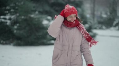 Neşeli kadın kar yağarken ormanda neşe içinde koşuyor. Rüzgar esiyor ve kar taneleri kış günü uçuyor.