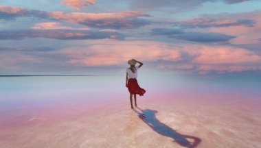 Rear view woman standing in beautiful pink lake with evening purple violet sunset sky