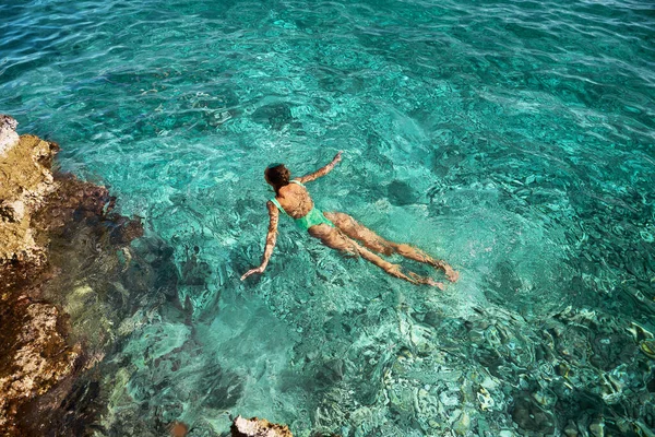 Voksen kvinne som svømmer i turkis sjøvann og nyter godt av tropisk stranddestinasjon – stockfoto