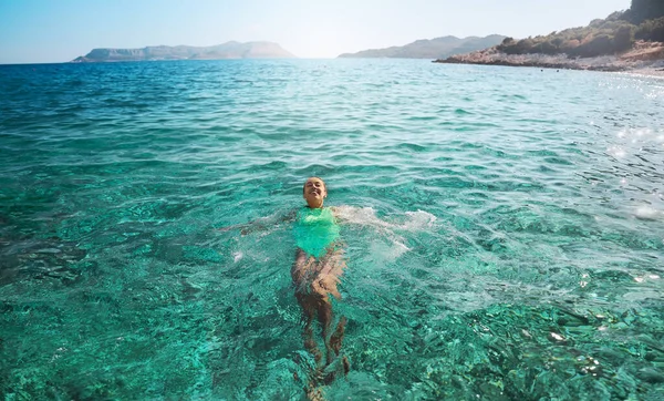 Hymyilevä nainen makaa selällään kelluva merivedessä, rentouttava lomalla — kuvapankkivalokuva