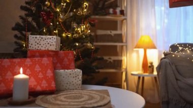 Bir grup kadının elleri gece odasındaki dekoratör Noel ağacının altındaki masaya şenlik kırmızısı koyuyor. Çelenk yakmak ve yanan mum Noel ruhları ve ruh hali yaymak.
