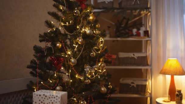 Decorações de árvore de Natal e caixas de presente no quarto à noite. Incrível guirlanda piscando irradiando espíritos de Natal e humor. Quarto escuro com natal e decoração de interiores do ano novo — Vídeo de Stock