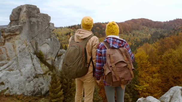 Vue arrière couple touristes se dresse sur fond de paysage d'automne avec des falaises dans le parc national Tustan, Ukraine. aimant tendre homme et femme voyageant ensemble et l'unité avec la nature — Video