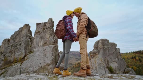 Пара туристов хипстеров стоит на осеннем ландшафтном фоне со скалами в национальном парке Тустань, Украина. Любящие нежные мужчина и женщина обижают друг друга. путешествия вместе и единство с природой — стоковое видео