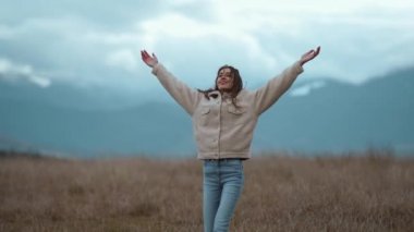 Açık kolları olan sakin bir kadın doğanın tadını çıkarıyor ve dağlarda özgürce dolaşıyor.