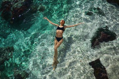 Mavi deniz suyunda yüzen mükemmel vücutlu, rahatlatıcı şehvetli kız manzarası.