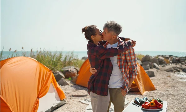 Lykkelig turistpar som omfavner og kysser. Romantisk campinghelg på stranda – stockfoto