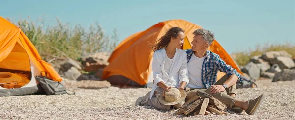 Et ungt, lykkelig par utendørs på stranden med telt under teltturen sammen – stockfoto