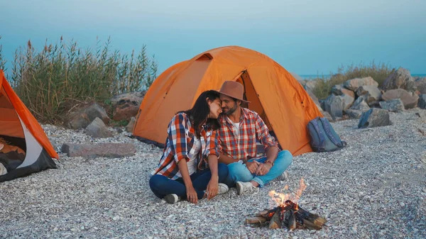 Et kjærlig par som tilbringer tid sammen ved bålet under romantiske campingferier med telt – stockfoto