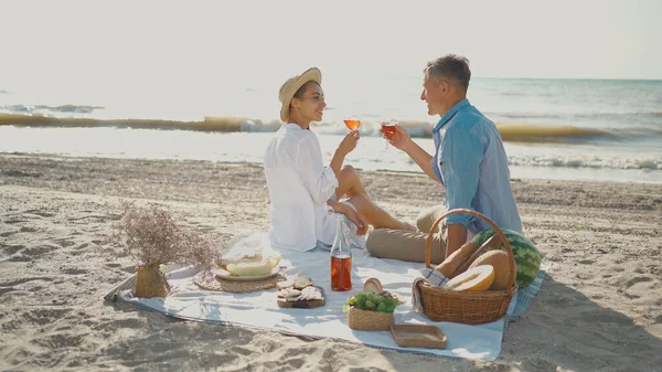 Tyylikäs aikuinen pari rakastunut juominen viiniä ja nauttia piknik päivämäärä rannalla — kuvapankkivalokuva