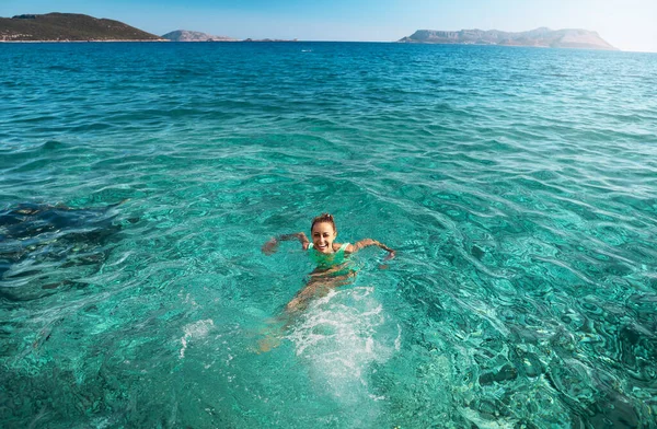 Turkuazda yüzen gülen kadının yüksek açılı manzarası. Tatilde deniz suyu.