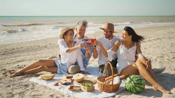 To par som drikker vin, lager toast og nyter piknik på stranden – stockfoto