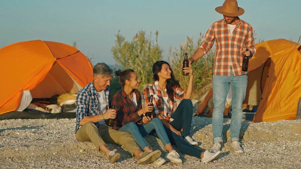 To voksne par som har strandfest i campinghelgen, drikker øl – stockfoto