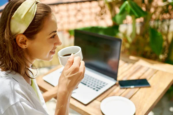 Nært ansikt, vakker kvinne, som drikker kaffe, nyter å bruke bærbar PC på kafeen – stockfoto