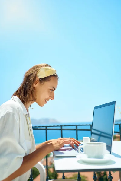 Freelancer nainen käyttää kannettavaa tietokonetta selailu verkossa, langattomissa kuulokkeet terassilla — kuvapankkivalokuva