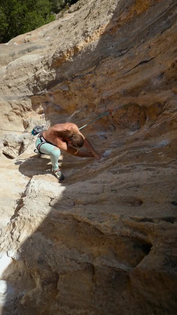年轻有力的攀岩运动员，长发爬上悬崖峭壁。男人爬得很辛苦，做了很长时间的艰难动作。极限运动，户外攀岩 — 图库视频影像