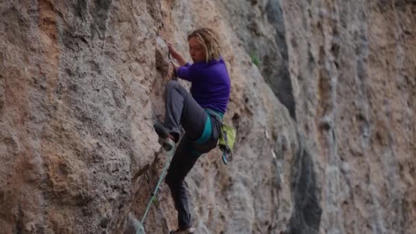 Atlético mulher adulta escalador de rocha sobe na parede de rocha da montanha, procurando e atinge detém. escalada ao ar livre, atividade ao ar livre e conceito de estilo de vida saudável — Vídeo de Stock