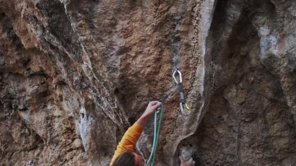 近视英俊男子攀岩者爬上高高的岩石悬崖，让人很难向上移动，紧紧抓住并剪断绳子，以快速拉住攀岩者 — 图库视频影像