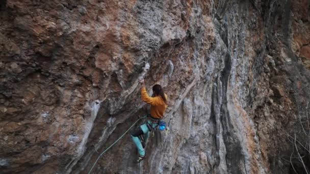 Cinemática cámara lenta Momentos de escalada en roca. escalador en sudadera amarilla en sube por un acantilado colgante. Hombre escalador tratando duro para agarrar asideros en tufas en ruta desafiante — Vídeo de stock