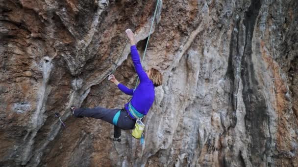 Slow motion lachende vermoeide vrouw rots klimmer opknoping op touw op harde uitdaging route op overhangende klif, rust en krijt handen — Stockvideo