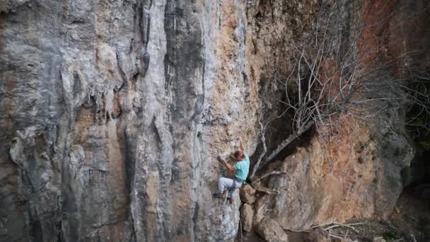 Vue de dessus l'homme adulte escaladeur grimpe sur la haute falaise rocheuse, ce qui rend difficile de se déplacer vers le haut, atteindre et saisir tenir et couper la corde — Video