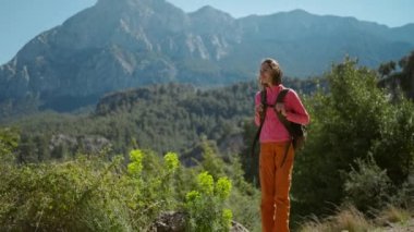 4k yavaş çekim güzel bayan yürüyüşçü güzel dağ manzarasında yürüyen, neşeli kız güneşli bir günde dışarıda yürüyüş yapıyor.
