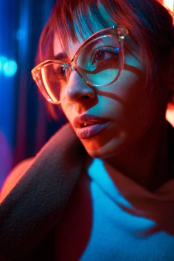 Caddedeki kırmızı ve mavi ışıklı ışığın yanında duran gözlüklü kadın.