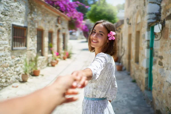 Очаровательная брюнетка с цветком в волосах улыбается и держит за руку своего парня — стоковое фото