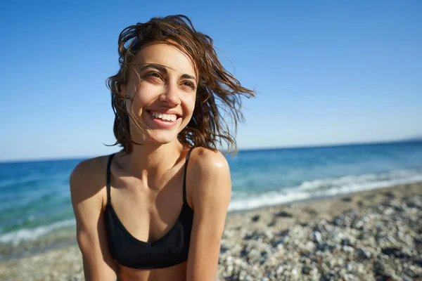 Outdoor shot of smiling young female model enjoying at sea beach against blue sky — Stock Photo, Image