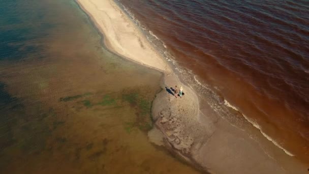 Cámara lenta aérea: pareja de viajeros caminando por la playa de arena entre el agua, Ucrania. — Vídeo de stock