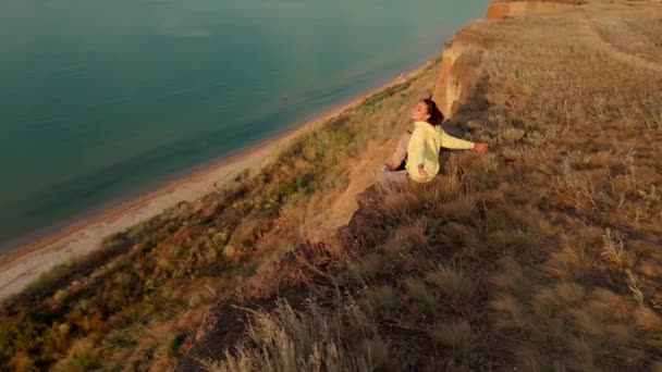 Glückliche unbeschwerte Frau mit Hund sitzt auf Klippe und genießt herrliche Aussicht über das Meerwasser — Stockvideo