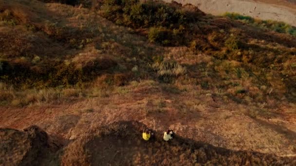 Aerial footage of two people sitting on the edge of cliff and overlooking bay of Black Sea — Stock Video