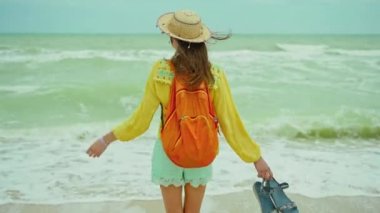 Panoramik manzara güzel okyanus plajı dalgalı ve bulutlu gökyüzü, şapkalı dikiz manzaralı kadın ve dalgalı saçlarıyla deniz manzarası