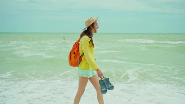 Аутентичный портрет счастливая молодая женщина в соломенной шляпе в жёлтой рубашке, развлекающаяся и чувствующая счастье во время прогулки по пляжу — стоковое видео