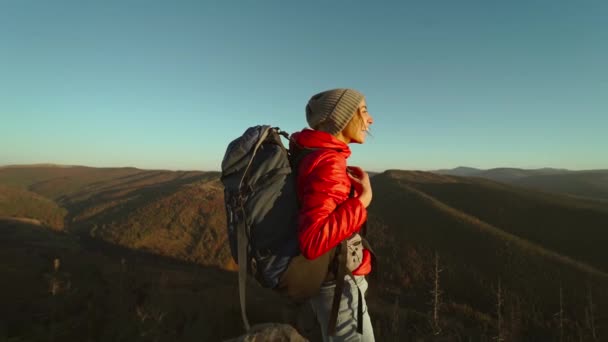 Happy woman on the peak of the mountain cliff edge under sunset light sky enjoying the success, freedom and bright future, slow motion — Stock video