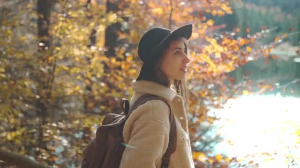 여성 관광객들은 화창 한 가을 날, 가을 숲 속을 걷는다. 날씨가 맑은 아침 산악 호수 주변 숲에서 배낭을 메고 산책하는 암컷, 옥외 생활을 하는 모험 — 비디오