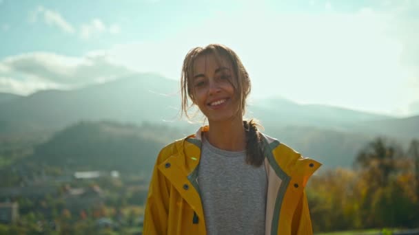 Joyful freedom ukrainian girl in yellow jacket standing against mountains and hills, sun lights over hand, feeling happiness. independent people in Ukraine. — Vídeos de Stock