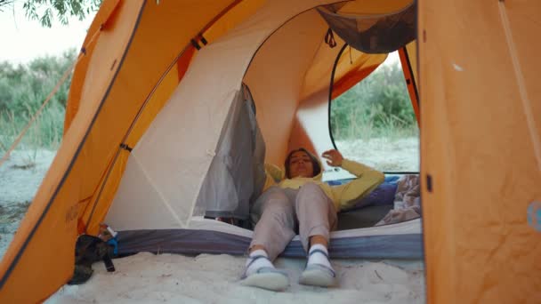 Mooie Oekraïense vrouw in oranje campingtent bewonderende zonsopgang. Reiskamp levensstijl en alternatieve hotelkamer vakantie concept. lokaal reizen in Oekraïne — Stockvideo