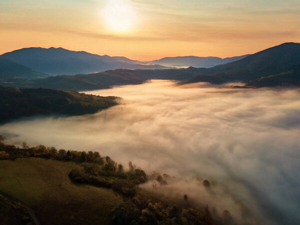 Beautiful mystery landscape with sunset sky and foggy forest between mountains hills. Stock Image