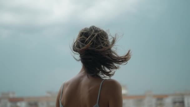 Rückansicht einer jungen Frau, die zu Hause im Nachtwind auf dem Balkon steht, dramatischer Himmel im Hintergrund. depressive Szene, Mädchen denken darüber nach, von hoch zu springen. Depressionen und psychische Erkrankungen, Selbstmordgedanken — Stockvideo