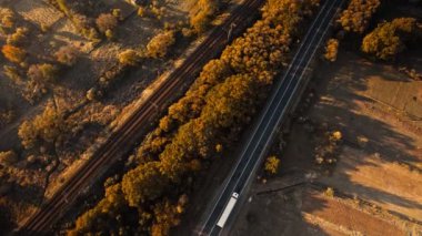 Batı Ukrayna, Karpatlar 'daki dağ vadisinde güneş doğarken kargo araçları ve demiryollarıyla aşağı bakan üst yol. Şehirler ve ülkeler arasında kargo taşıma ve teslimatı