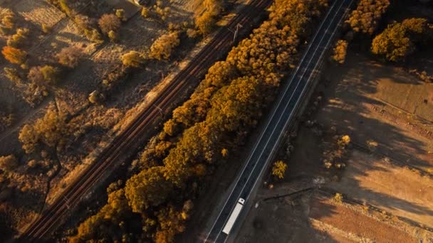 Top down view road with cargo vehicles and rails at sunny sunrise in mountain valley in Carpathians, Δυτική Ουκρανία. Μεταφορά και παράδοση φορτίου μεταξύ πόλεων και χωρών — Αρχείο Βίντεο