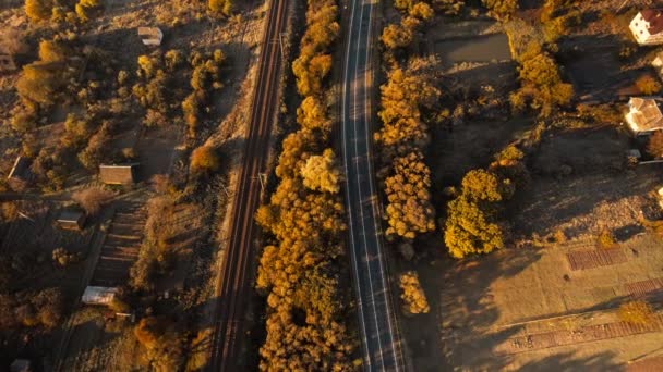 Puncak udara di bawah melihat jalan aspal dan kereta api kosong saat matahari terbit di sisi negara di lembah pegunungan di Carpathians, Ukraina Barat. logistik, link transportasi, jalan dan mode transportasi — Stok Video