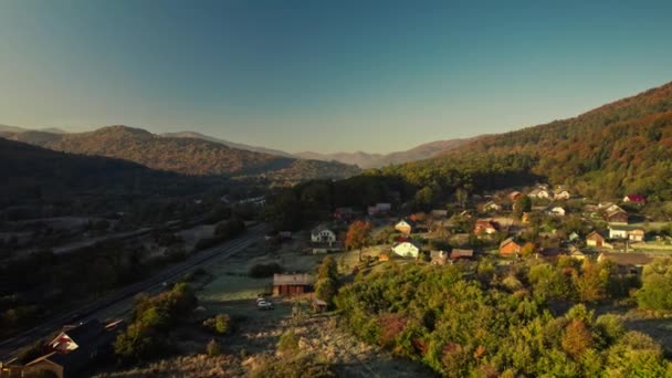 Légi táj ukrán hegyi falu Kárpátok, Nyugat-Ukrajnában. Út, vasút, vidéki házak és régi fapadló felülről. szépség a természet Ukrajnában — Stock videók