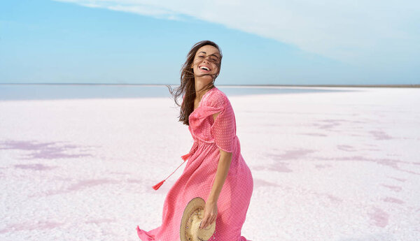 Motion portrait happy woman in pink dress playful having fun on desert beach of pink lake Royalty Free Stock Photos
