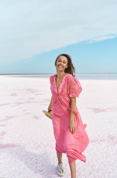 Happy emotionally woman wearing pink dress, walking by windy salt beach of pink lake Stock Image